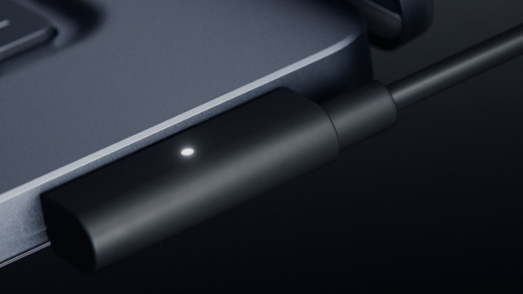 Close-up of a magnetic charging connector attached to the edge of a laptop