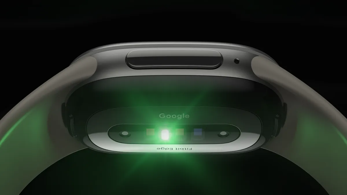 The underside of a Fitbit Edge, with its heart-rate sensor lit green and the Google and Fitbit Edge markings