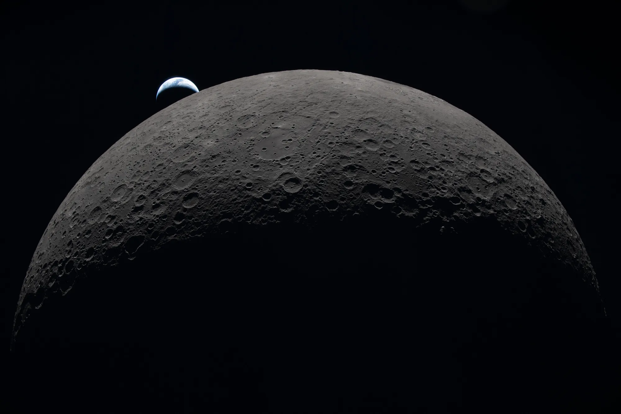 The Moon's curved edge with a crescent Earth setting behind it